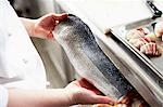 A chef holding a raw fish fillet