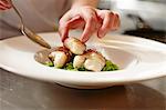 A chef arranging fish in bacon on a plate