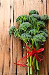 Broccolini with a red ribbon on a wooden surface