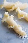 Fresh Gigli Toscani pasta on a floured marble surface