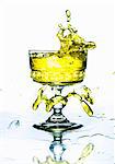 A yellow drink splashing from a glass