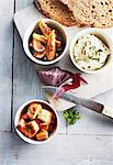 Salmon, slices of bread, cream cheese with herbs, figs and onions on a chopping board