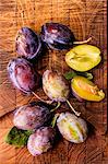 Fresh plums on a wooden board (seen from above)