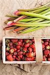 Strawberries in a wooden basket next to rhubarb