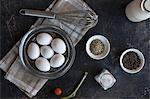 Eggs, spices, a spring onion, a cherry tomatoes and a whisk