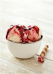 A bowl of icecream with raspberry sauce and a wafer cigar