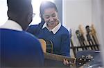 Students playing acoustic guitar in classroom