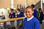 Portrait of smiling elementary school girl wearing blue school uniform standing in school corridor