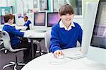 Portrait of primary school girl wearing blue school uniform using computer