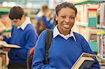 Portrait of smiling female student holding books in library