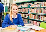 Portrait of smiling schoolgirl doing homework in library