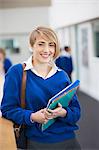 Portrait of smiling female student wearing school uniform standing in corridor