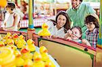 Parents with two children having fun with fishing game in amusement park