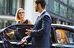 Chauffeur opening car door for businesswoman