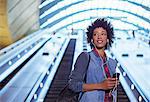 Woman listening to earbuds on escalator