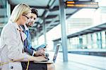 Business people using laptop at train station