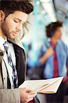 Businessman reading newspaper on train