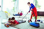 Superhero vacuuming around family in living room