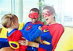 Superhero parents playing with daughter on living room sofa