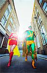Low angle view of superhero couple running on city street