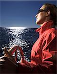 Woman Steering Boat while Sailing off Coast of Maine, USA