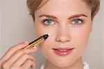 Portrait of a beautiful woman applying concealer