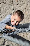Smiling young boy climbing chain playground