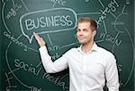Young business man standing in front of a blackboard with a business plan