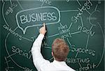 Youn man writing down business ideas on blackboard