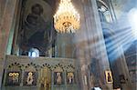 Inside of ancient church includes fresco, stone iconostasis, holy gates and the grand chandelier on center. Shoots of sunlight penetrate intrerior space of church.