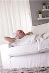 self-confident mature man relaxing on a sofa in a white living room