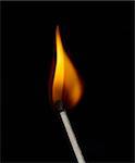 Build a fire. Lighted match on a black background