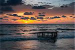 Tropical Beach with Empty Cage in the Sea at Colorful Sunset