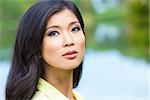 Outdoor portrait of a beautiful young Chinese Asian young woman or girl by a lake with reflections