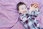 Cute Young Mixed Race Boy Playing With Football Outside On Picnic Blanket.