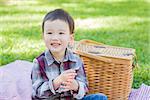 Cute Young Mixed Race Boy Sitting in Park Near Picnic Basket.