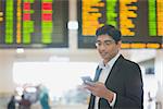 Asian Indian Business man checking on smartphone, doing online web check in at the airport .