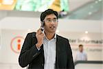 Asian Indian businessman walking by information counter,  talking on phone.