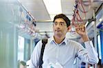 Asian Indian business man taking ride to work, standing inside train.