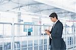 Asian Indian businessman using tablet computer while waiting train at railway station.