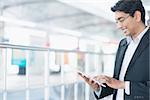 Asian Indian businessman using tablet pc while waiting train at railway station.