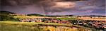 Landscape with Several Populated Areas under Cloudy Sky and Rainbow