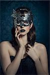 Beautiful, mysterious, sensual, woman with brown old fashion hairstyle, silver mask and dark makeup.