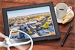 drone aerial photography concept - reviewing aerial pictures of Fort Collins downtown on a digital tablet with a drone rotor and cup of coffee