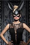 Sexy, beautiful woman in black dress and carnival, black rabbit mask with smokey eye makeup.