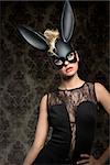 Sexy, beautiful woman in black rabbit mask and back dress with perfect dark make up.