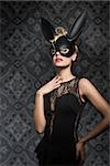 Sexy, pretty, elegant blonde woman in black dress and rabbit mask with dark make up.