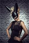 Sexy, beautiful, hot, blonde woman in elegant black dress with black rabbit mask and dark makeup.