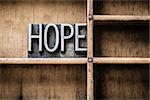 The word "HOPE" written in vintage metal letterpress type sitting in a wooden drawer.