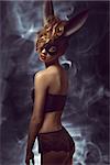 curly woman posing in Easter fashion glamour shoot with black bizarre bunny mask and stylish lace lingerie